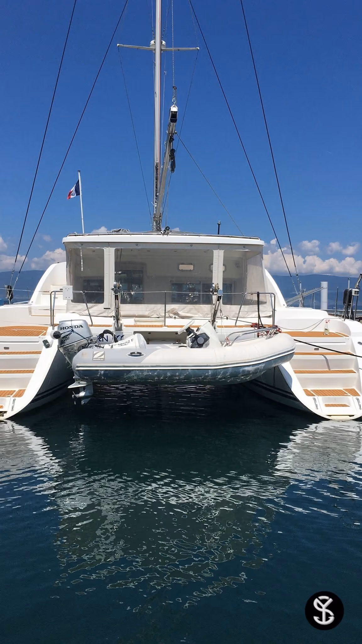 Catamaran amarré à quai sur le lac Léman, vu depuis l’arrière, son annexe relevée
