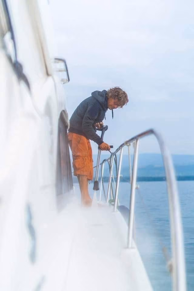Stéphane Badea au travail sur le passavant d'un yacht à moteur, le lac Léman en arrière-plan